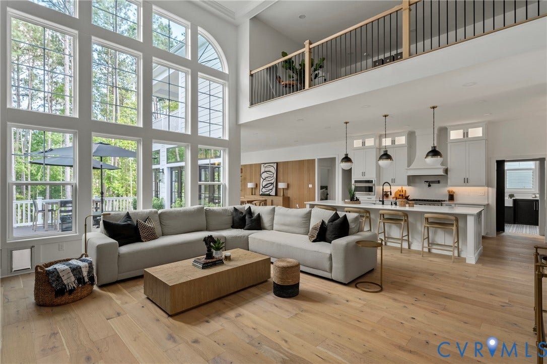 18312 Barrin Court, Barrington, Moseley, VA 23120 Living area with two-story ceiling, light wood-finish flooring, and a full wall of tall windows including an arched transom