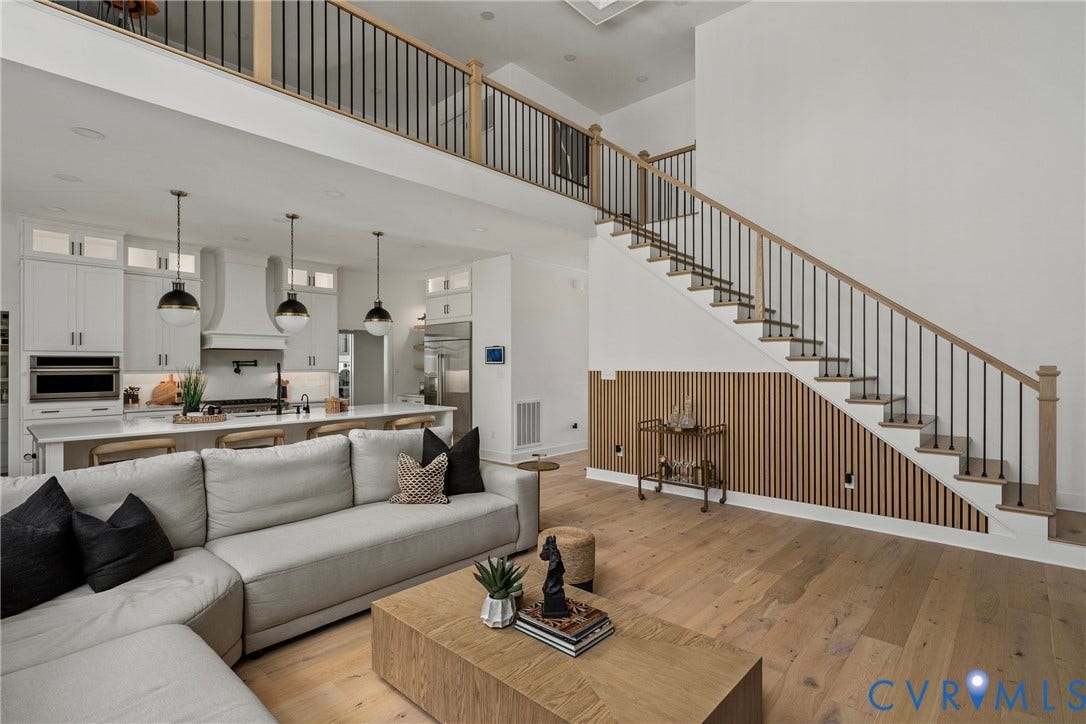 18312 Barrin Court, Barrington, Moseley, VA 23120 Open-concept living space featuring light wood-finish flooring, a contemporary staircase with iron balusters and a wood handrail, a kitchen island with pendant lighting, white cabinetry, and stainless steel appliances