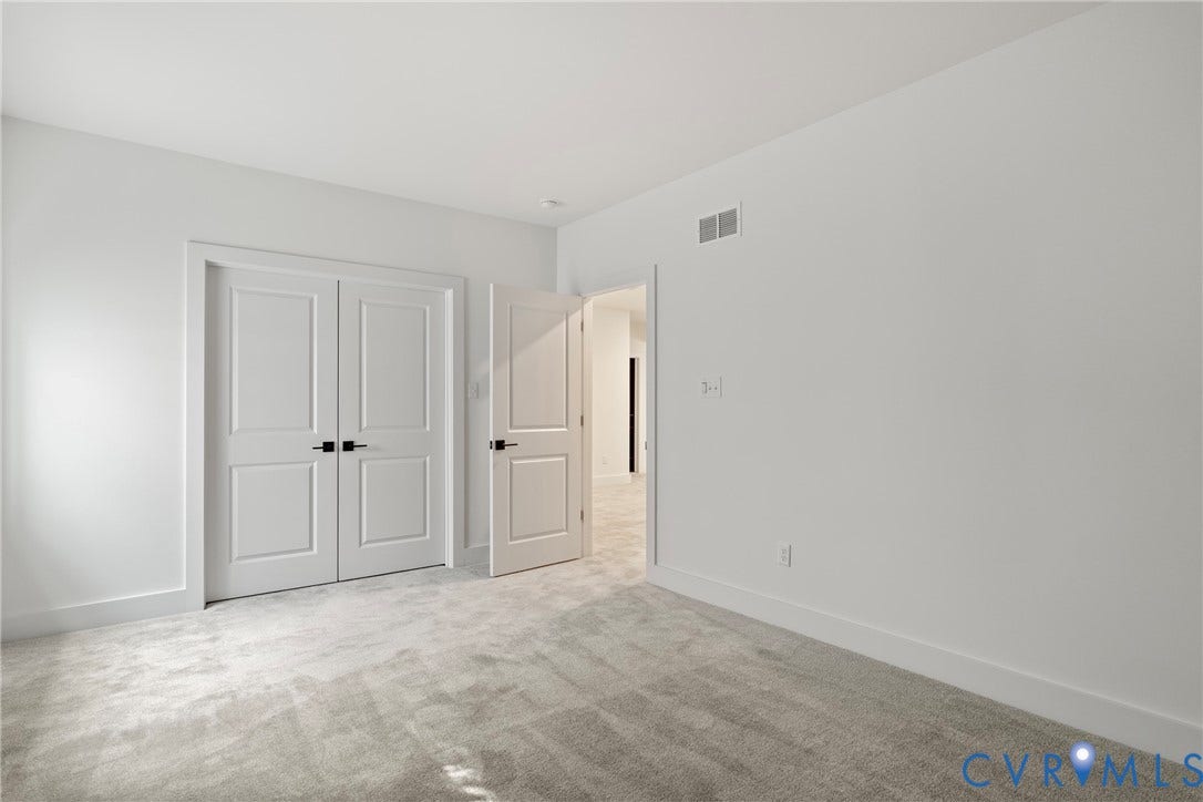 18312 Barrin Court, Barrington, Moseley, VA 23120 Neutral wall paint with contrasting white trim, grey patterned carpet flooring, and two panel interior doors with matte black hardware