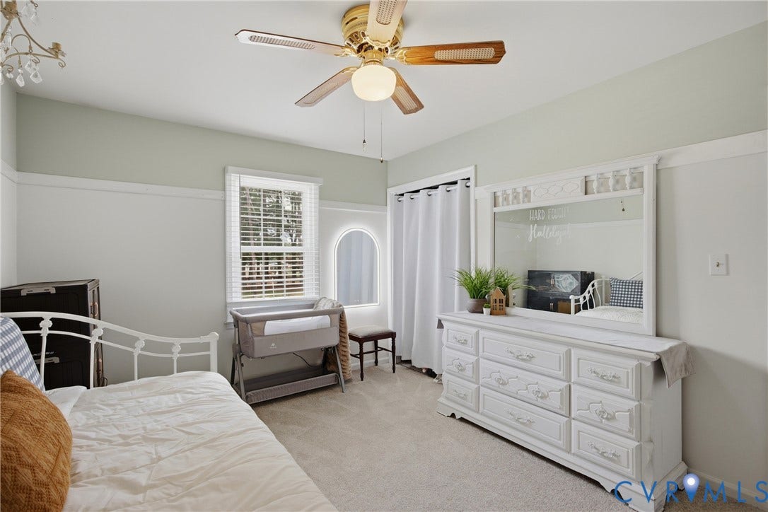 Wall-to-wall carpeted room featuring a window with blinds, a secondary arched window, and a ceiling fan with integrated lighting