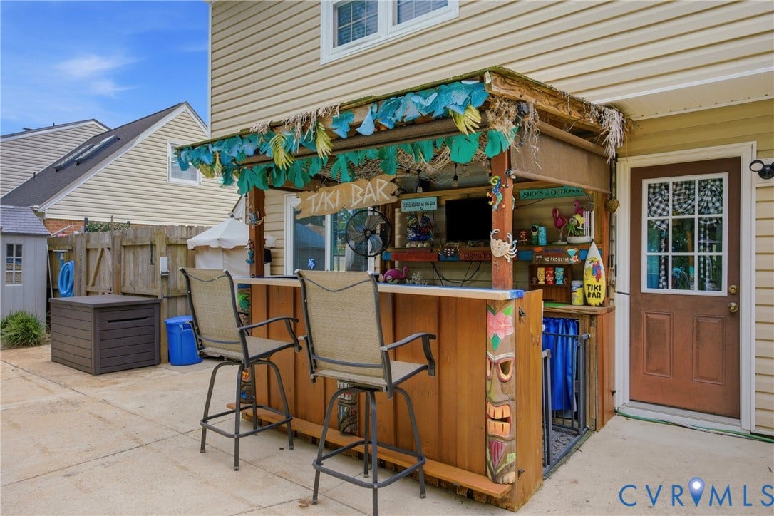 Outdoor bar structure with a wood-finish counter and built-in shelving, situated on a concrete patio