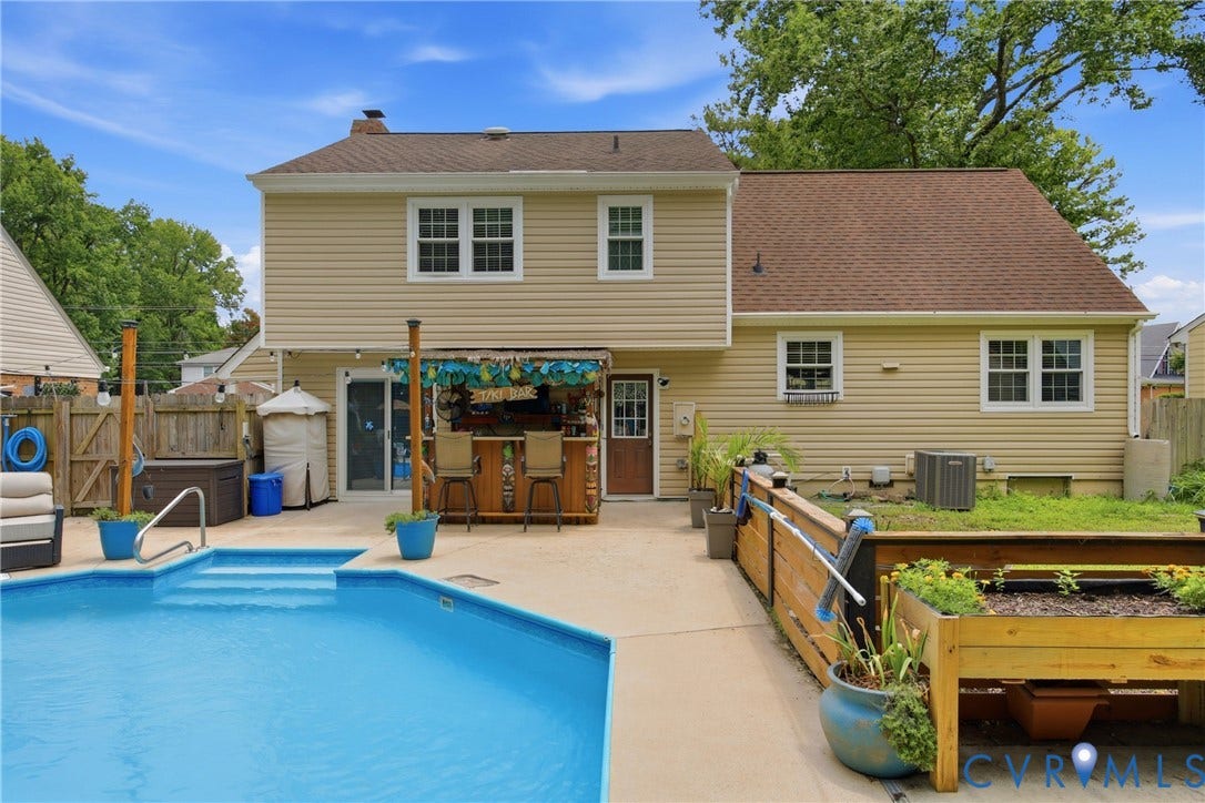 Backyard oasis featuring an in-ground swimming pool with steps, an outdoor bar area with stools, and a separate hot tub