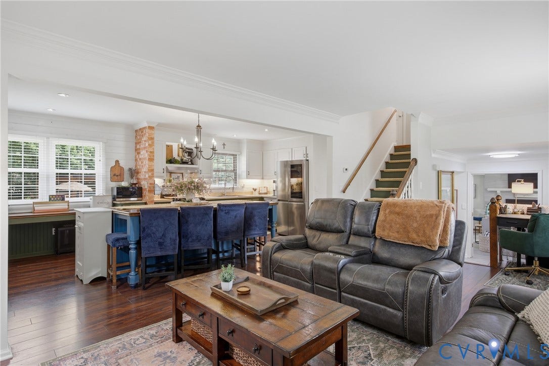 Open-concept living space featuring wood-finish flooring and crown molding
