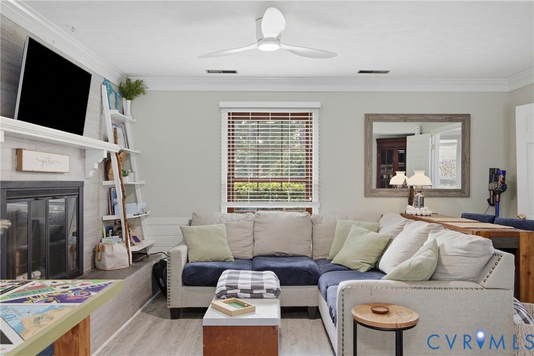 Living area featuring a modern ceiling fan, wood-finish flooring, and a fireplace with a mantel