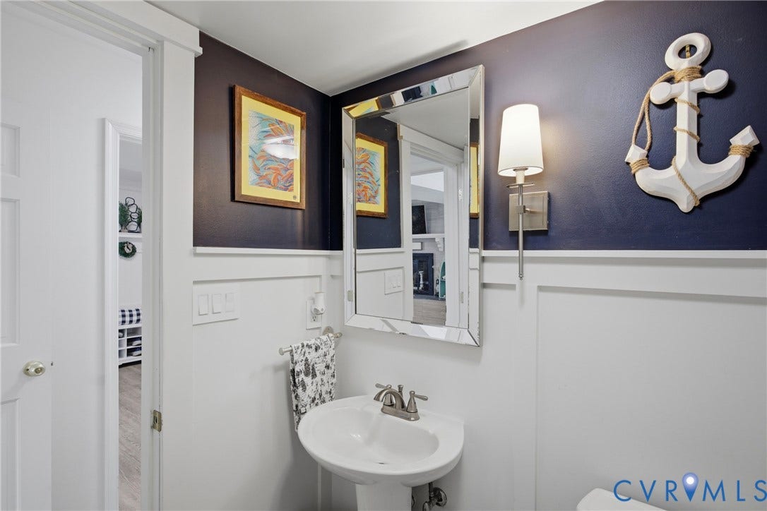 Pedestal sink with chrome faucet, framed mirror, and wall sconce