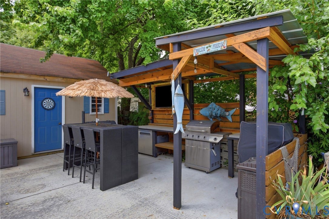 Outdoor entertainment area featuring a covered patio, built-in counter space, and an integrated grilling station
