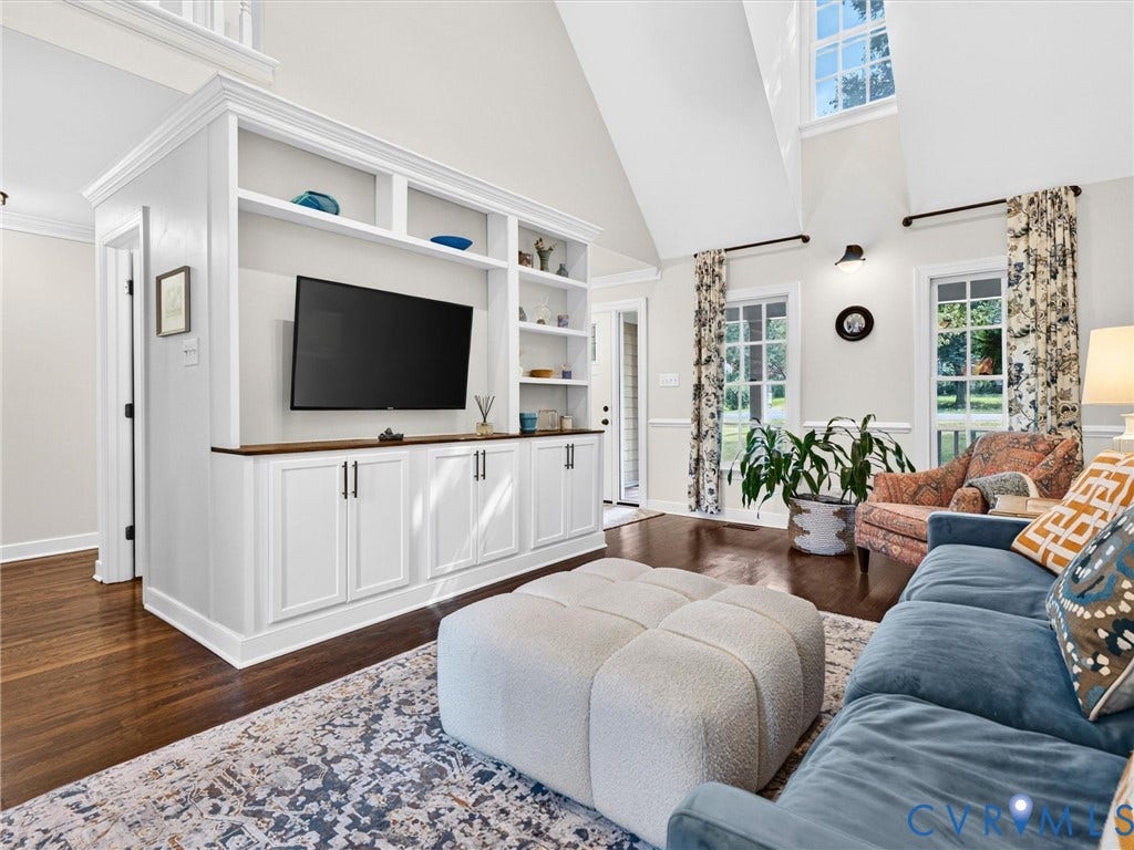 Vaulted ceiling, built-in entertainment center with open shelving, dark wood-finish flooring, and transom windows