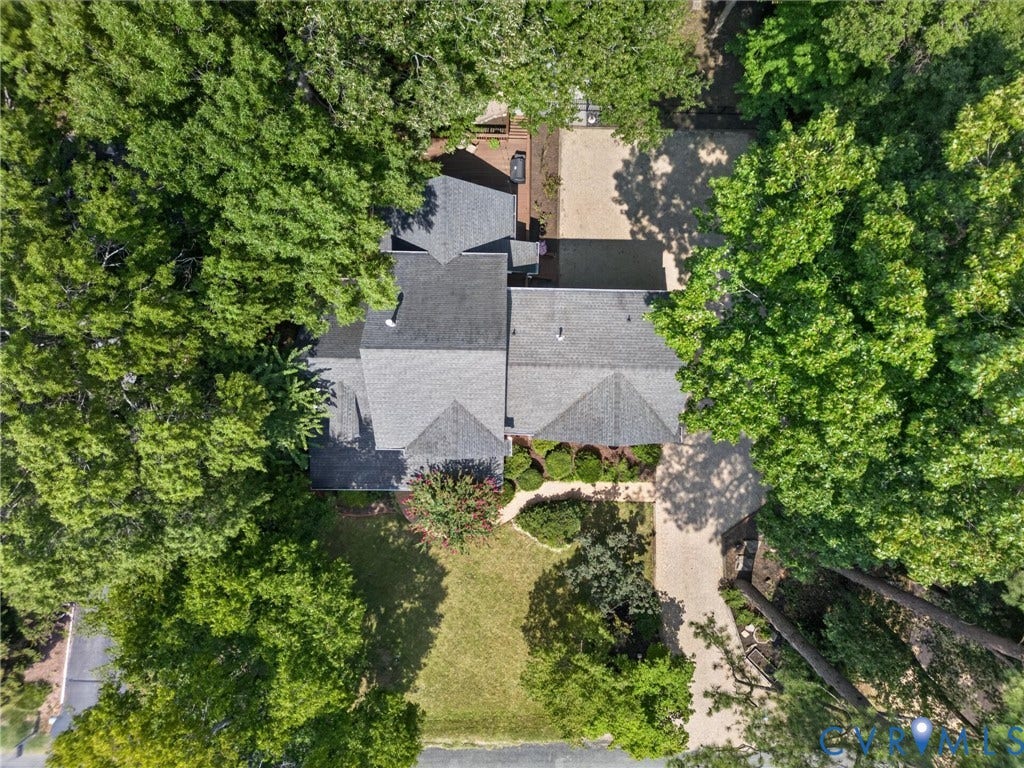 Aerial property overview featuring a multi-gabled roofline, mature tree canopy, and expansive gravel driveways