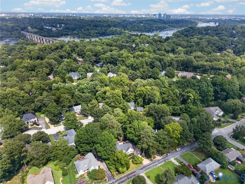 Expansive treed landscape with residential properties, featuring a distant bridge and urban skyline