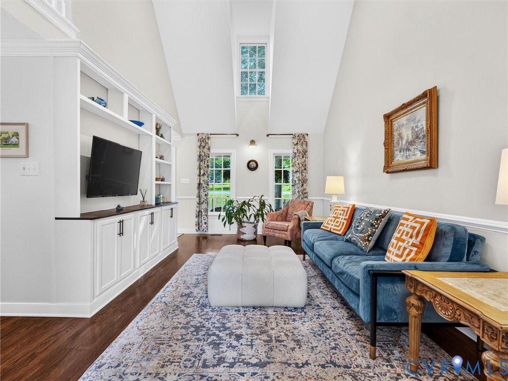 Vaulted ceiling with transom window, built-in cabinetry with open shelving and closed storage, dark wood-finish flooring, and white trim work