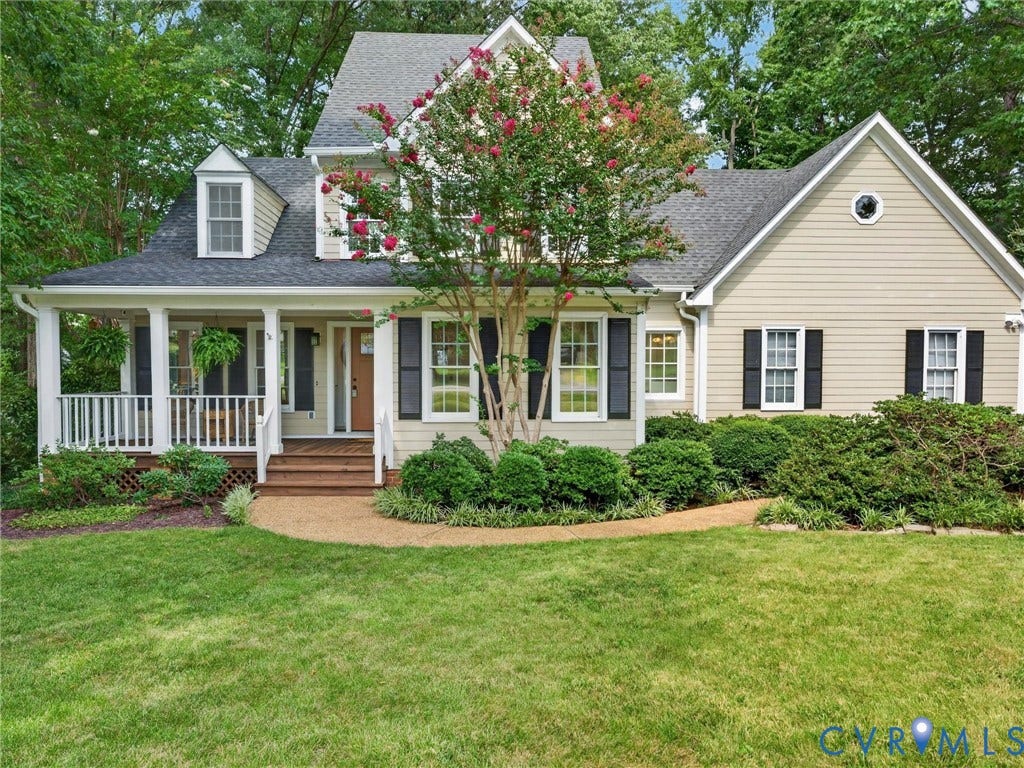 Covered front porch, dormer window, gabled roofline, front landscaping, and a manicured lawn