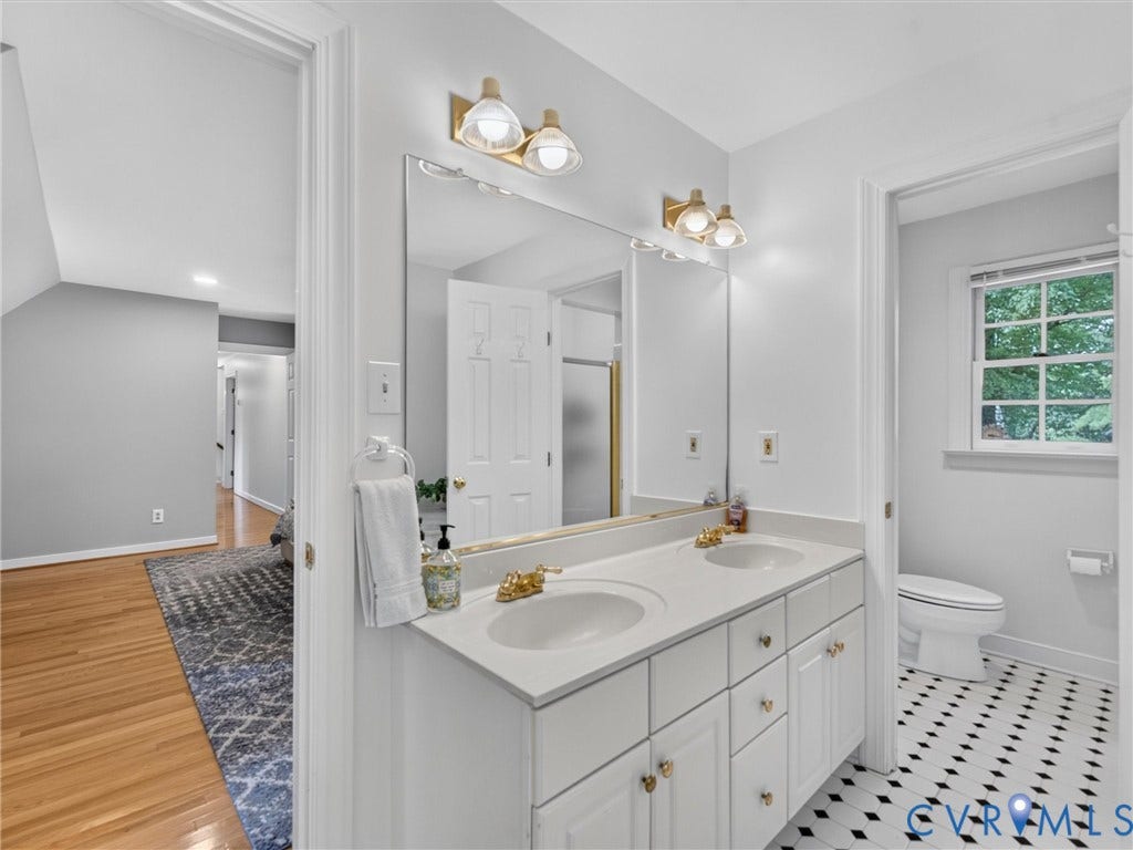 Dual vanity with integrated sinks, gold-finish fixtures, and a large mirror