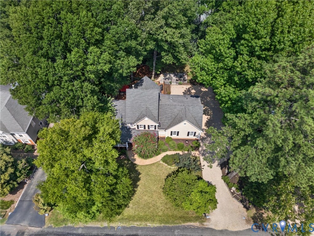 Expansive lot with mature trees, gravel driveway, and landscaped front yard