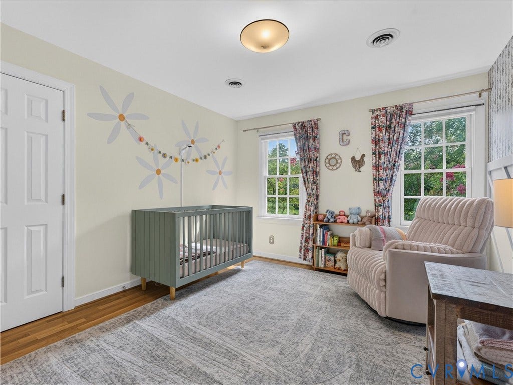 Wood-finish flooring, white paneled door, ceiling-mounted light fixture, and double-hung windows