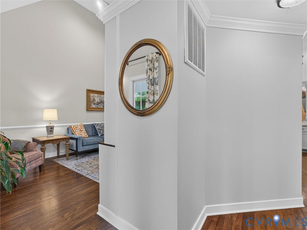 Vaulted ceiling with crown molding, wood-finish flooring, and chair rail detailing