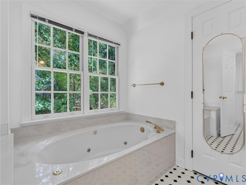 Soaking tub with gold-tone fixtures, surrounded by a light-toned countertop