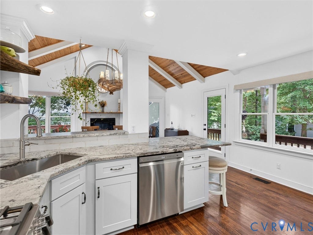 Kitchen featuring white shaker cabinetry, stainless steel appliances, granite countertops, and wood-finish flooring