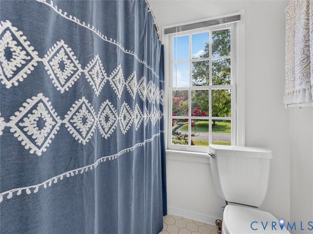 White framed window, white toilet, and hexagonal floor tiling