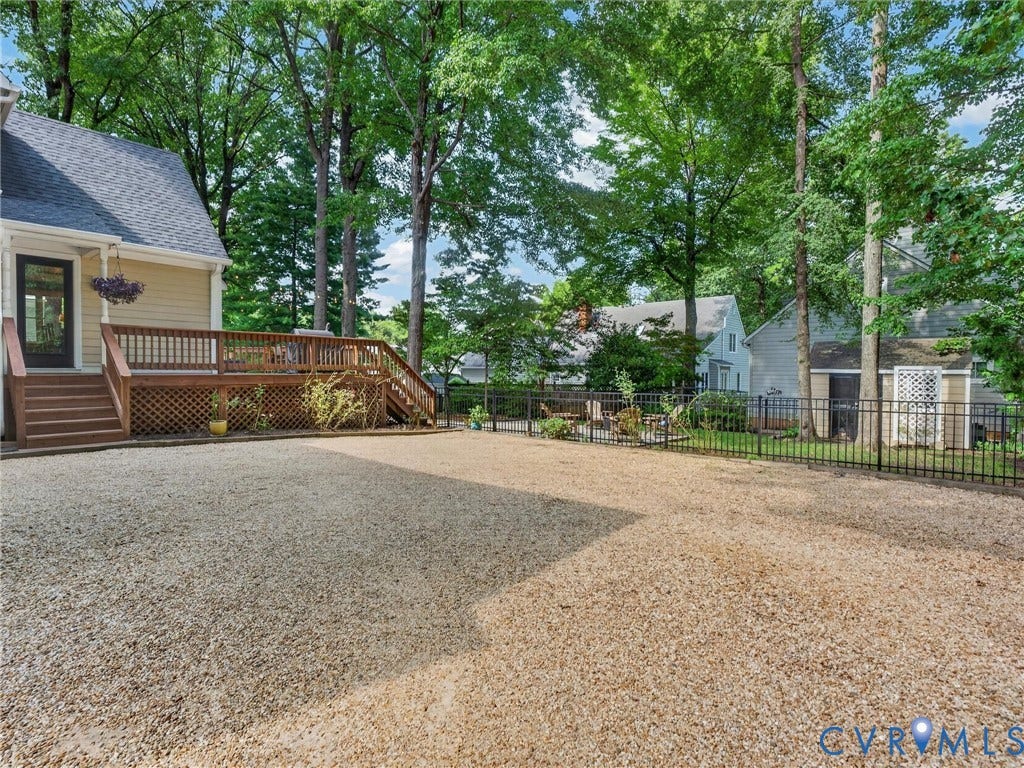 Spacious gravel yard with perimeter fencing, featuring a multi-level wood deck with lattice skirting and stairs