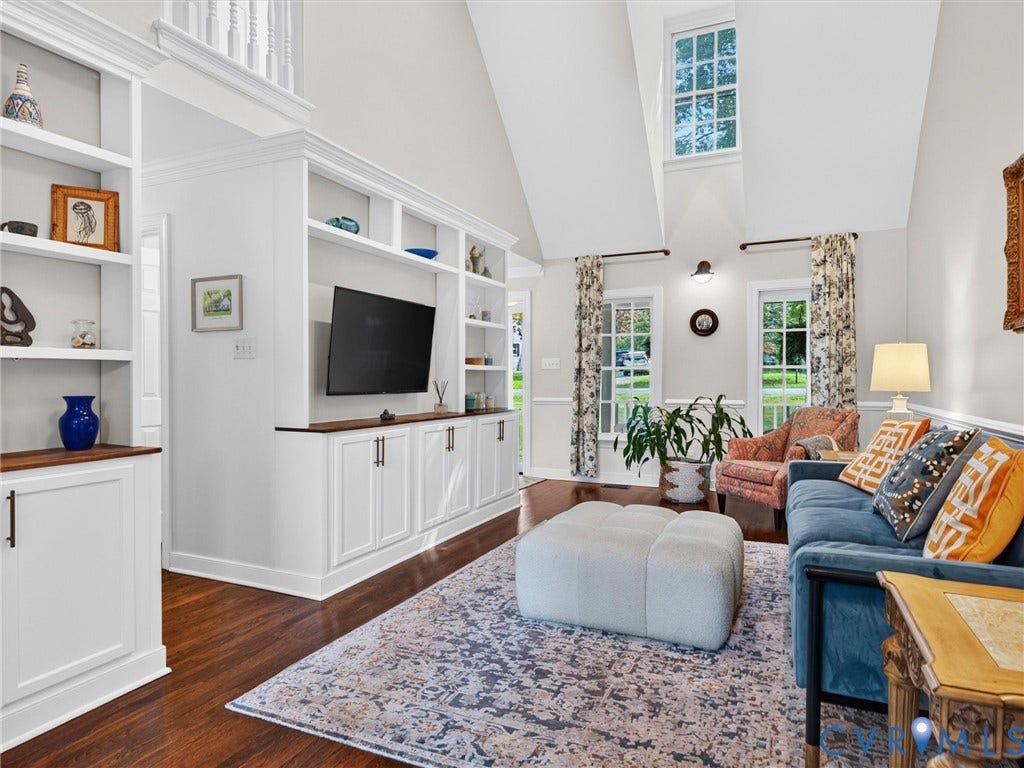 Custom built-in cabinetry and shelving, vaulted ceiling, wood-finish flooring, upper transom window, and white balustrade