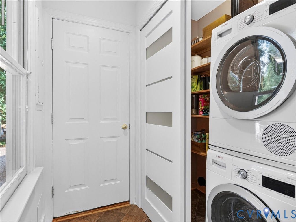 Stacked laundry appliances and wood-finish shelving, with a sliding door featuring frosted glass panels