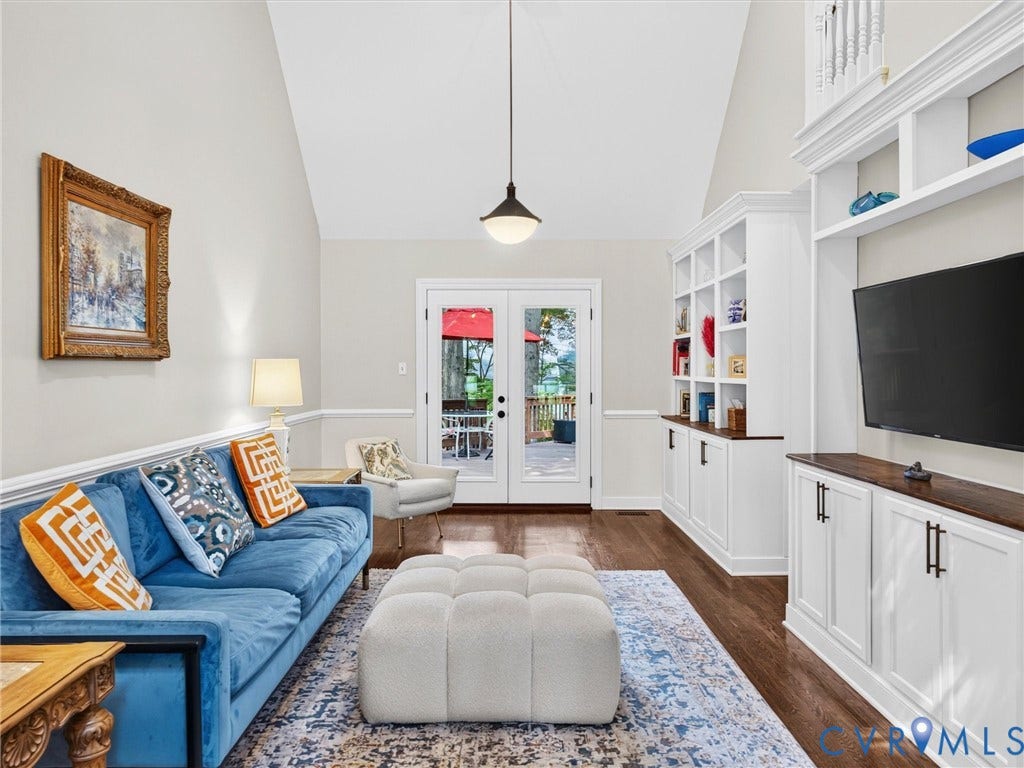 Vaulted ceiling, wood-finish flooring, white built-in cabinetry with wood countertops, glass-paned French doors, and a pendant light fixture