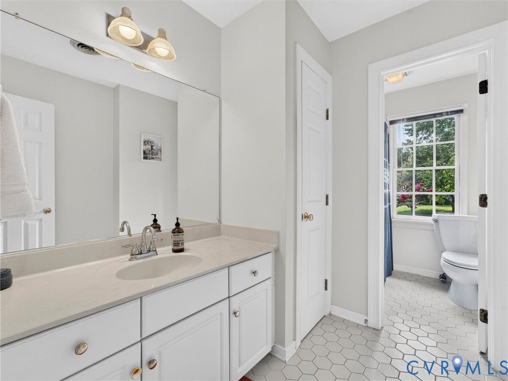 Bathroom featuring a white vanity with an integrated sink, polished chrome faucet, and a large wall-mounted mirror