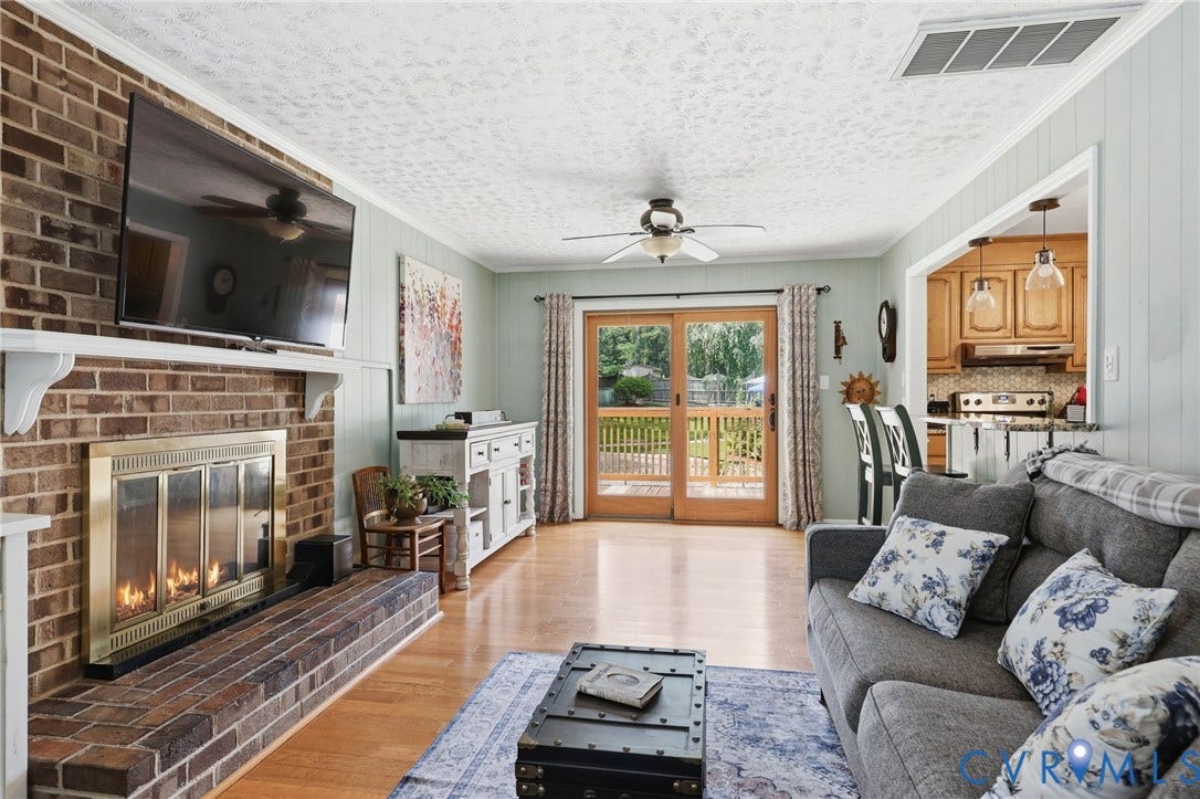 3300 Woodsong Drive, Midlothian, VA 23112 Living area featuring a brick fireplace with a brass-framed firebox, wood-finish flooring, and sliding glass doors to the exterior deck
