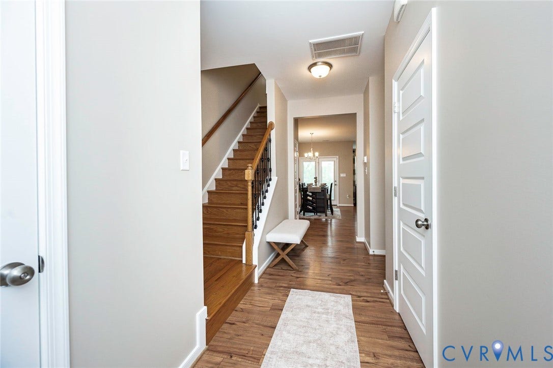7205 Desert Candle Drive, Moseley, VA 23120 Entryway featuring luxury flooring, a stairway with wood treads and wrought iron balusters, and a paneled interior door