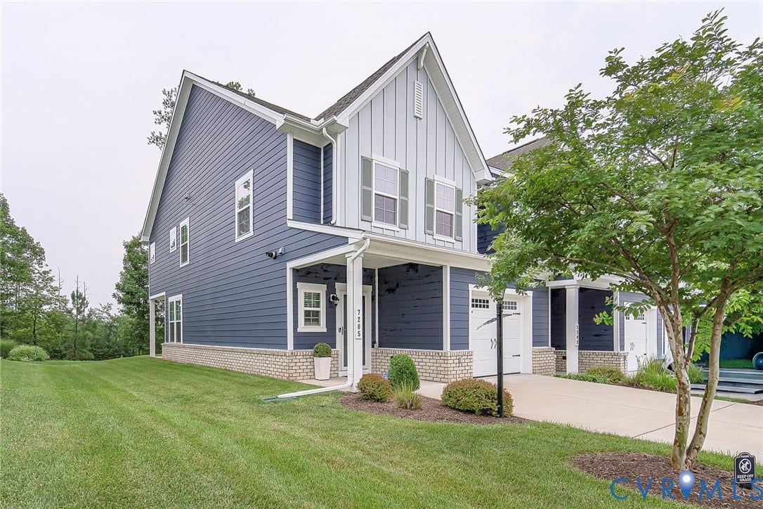 7205 Desert Candle Drive, Moseley, VA 23120 Two-story residence featuring blue siding with a contrasting light gray gable, white trim, and a partial brick facade