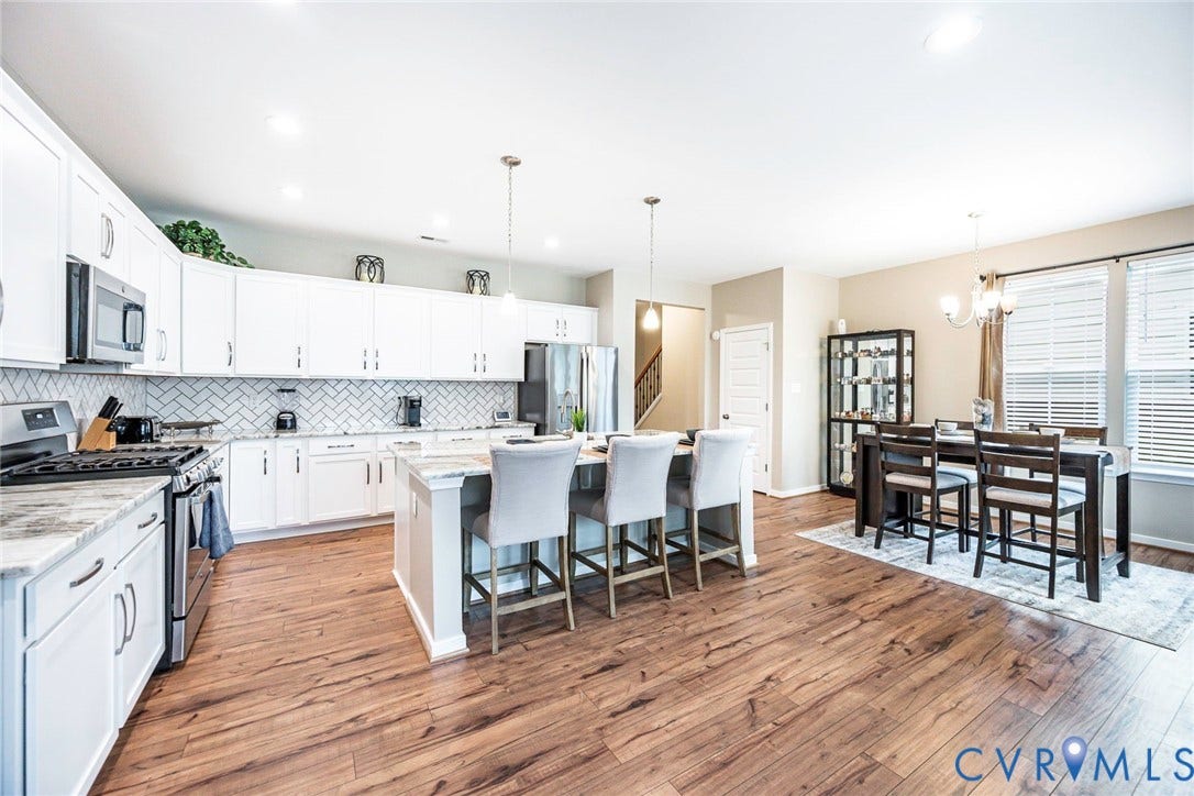 7205 Desert Candle Drive, Moseley, VA 23120 Open-concept kitchen and dining area featuring white cabinetry, a herringbone tile backsplash, and a central island with pendant lighting