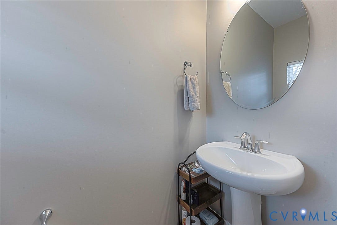 7205 Desert Candle Drive, Moseley, VA 23120 Pedestal sink with a polished chrome faucet and a large oval wall mirror