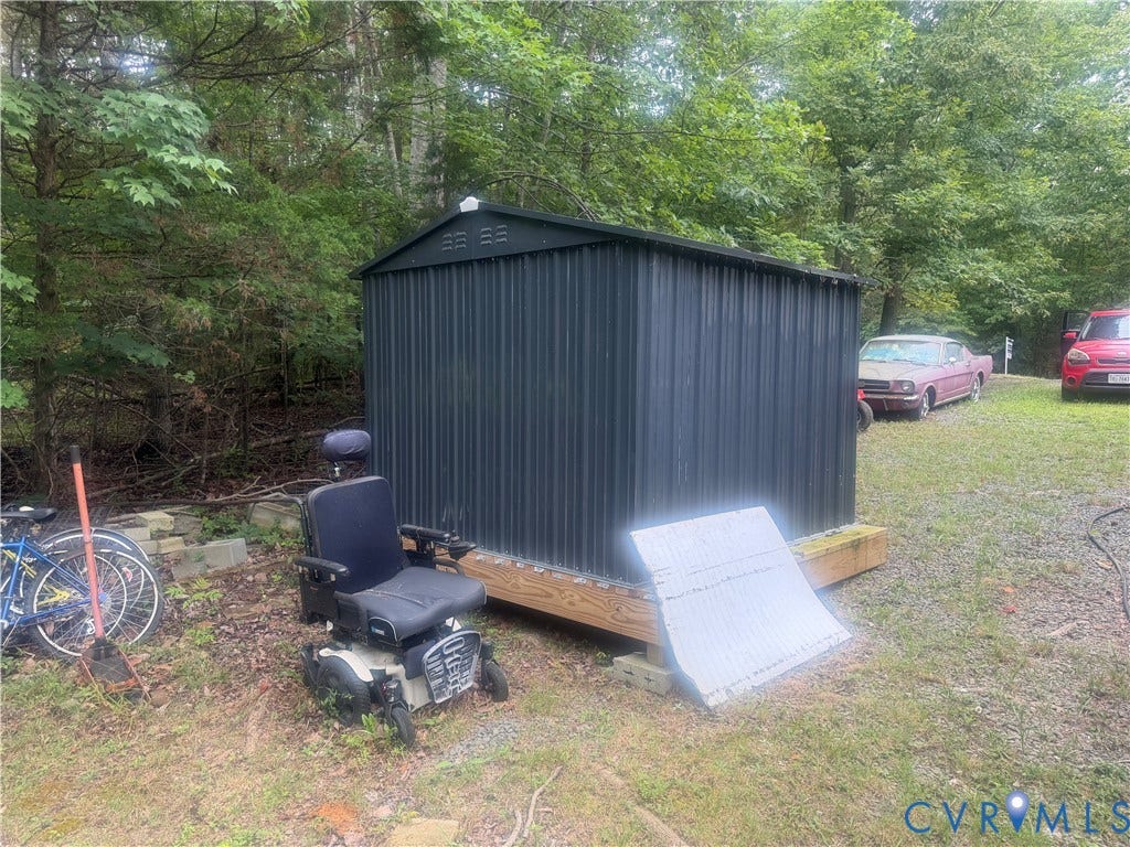652 Mallorys Ford Road, Cool Springs, Louisa, VA 23093 Utility shed with dark corrugated metal siding, supported by a wood plank foundation