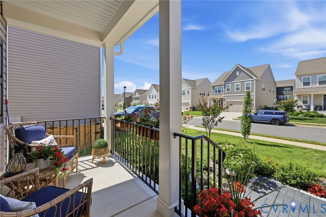 Covered front porch with white columns, black railings, and concrete flooring