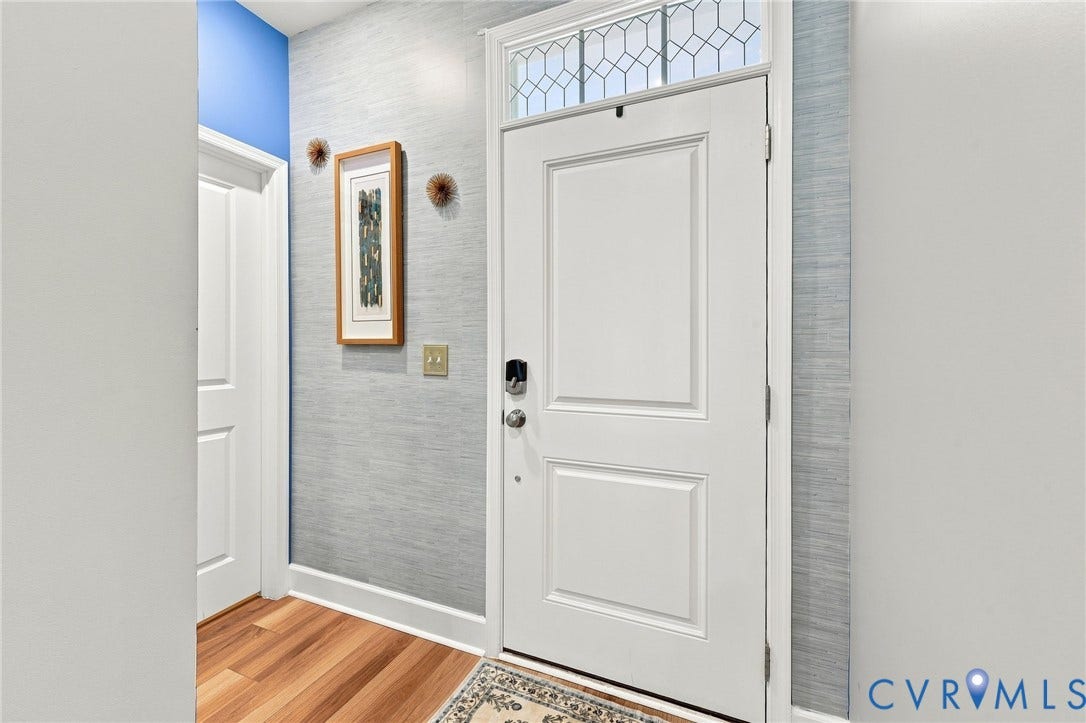 Entryway featuring a paneled white door with transom window, wood-finish flooring, and textured wall covering
