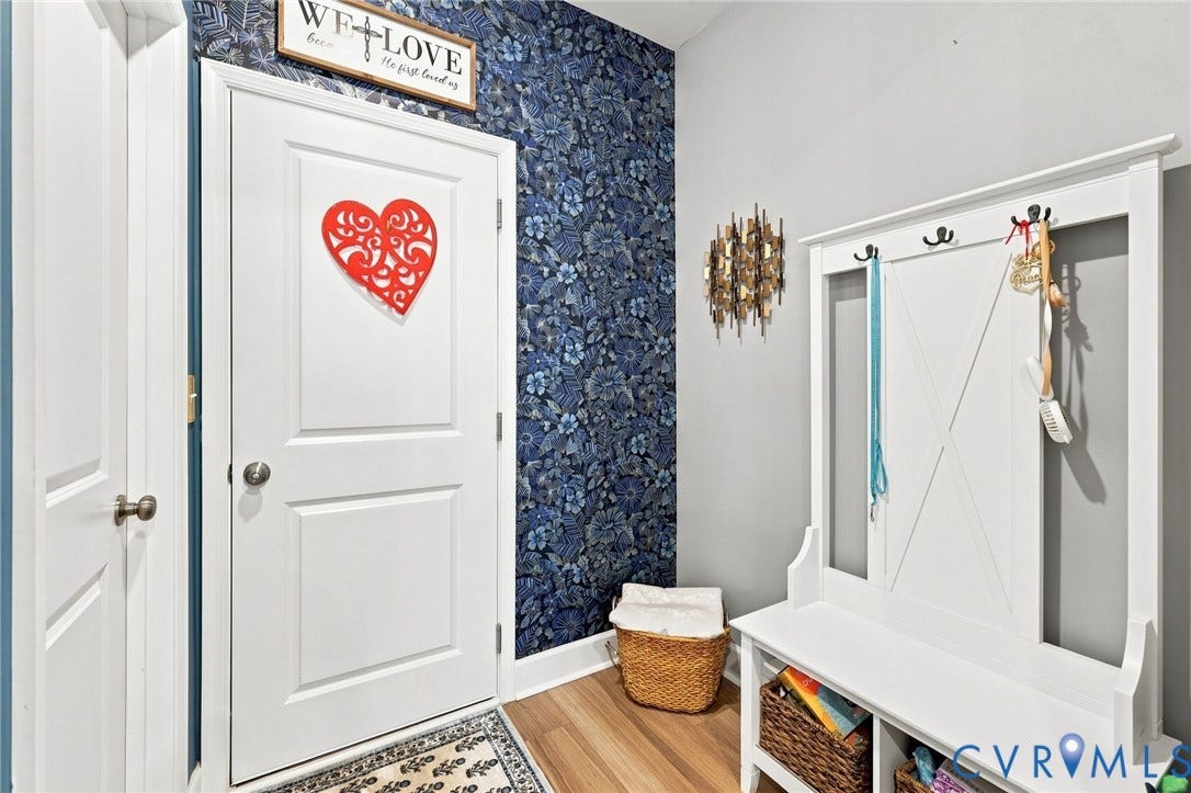 Entryway featuring a white paneled door, wood-finish flooring, and a decorative accent wall with blue botanical wallpaper