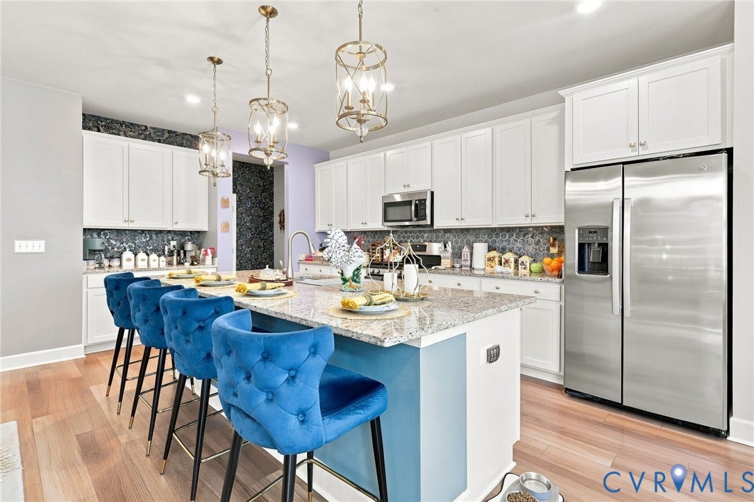 Contemporary kitchen featuring white cabinetry, stainless steel appliances, and a light-filled layout anchored by a light blue island with seating for four