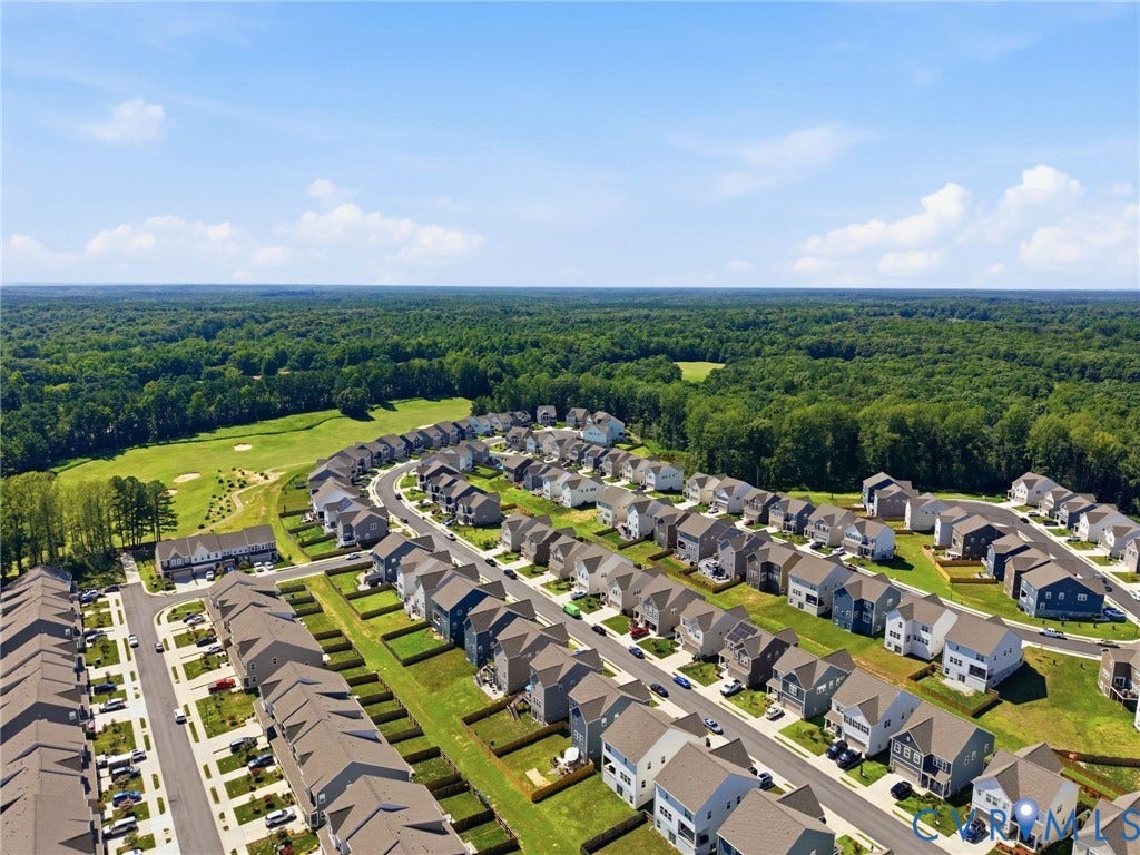 Aerial perspective showcasing a residential community with numerous single-family homes and townhomes