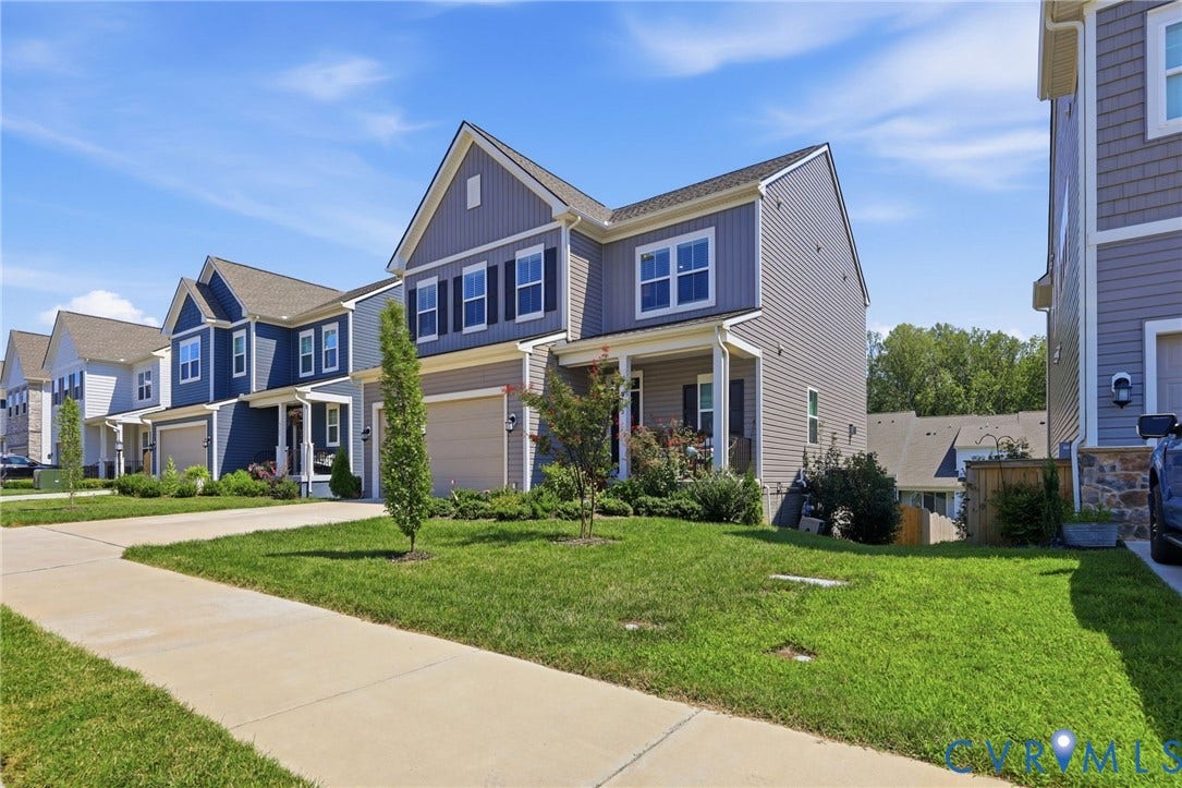 Modern residential exterior featuring blue siding, white trim, and a covered front porch