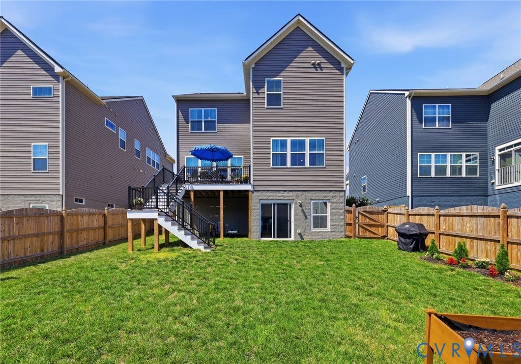 Spacious backyard featuring a professionally maintained lawn, wooden privacy fencing, and a multi-level deck with blue umbrella