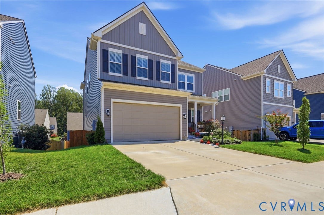 Two-story colonial with gray fiber cement siding and tan trim featuring a two-car attached garage with a neutral-finish door