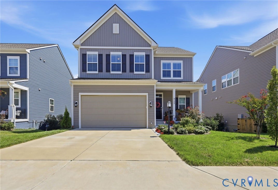 Contemporary two-story residence featuring a combination of horizontal siding and vertical paneling, an attached two-car garage, a covered front porch, and a well-maintained front lawn with established landscaping
