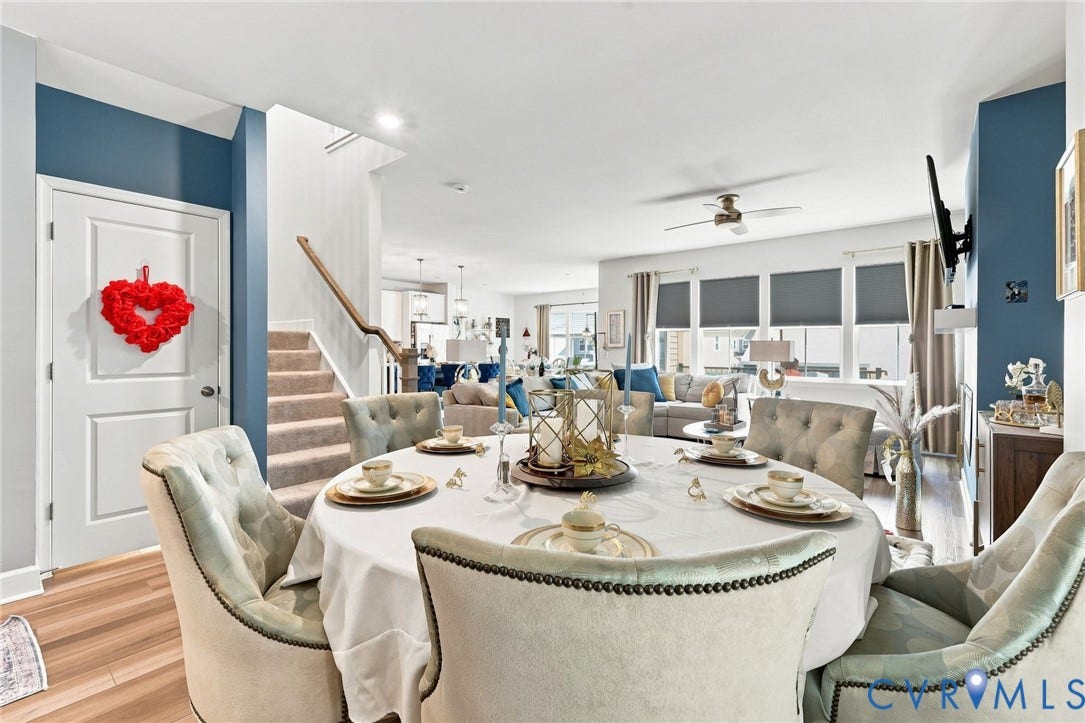 Elegant dining room showcasing a round table with nailhead-trimmed upholstered chairs, white tablecloth, and place settings