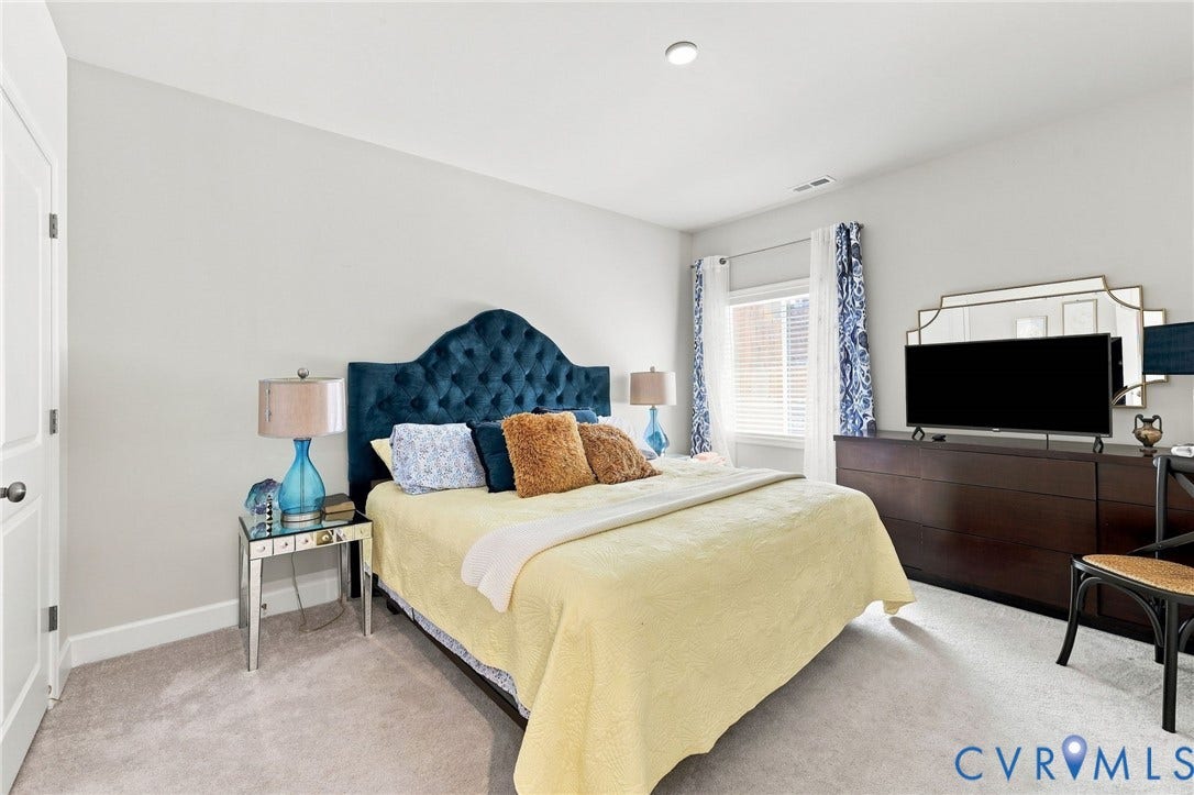 Carpeted bedroom featuring a single window with blinds, recessed lighting, and a white interior door