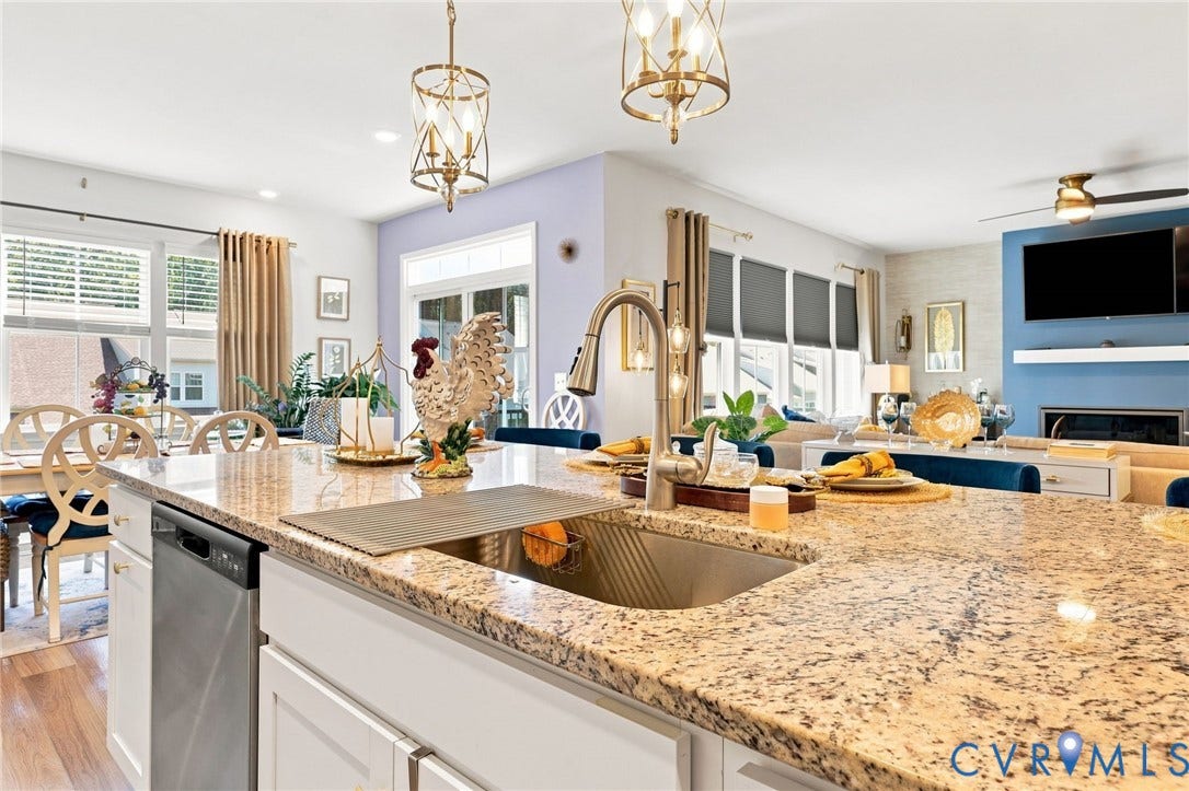 Expansive kitchen island featuring a granite countertop, undermount stainless steel sink with a high-arc faucet, and integrated dishwasher