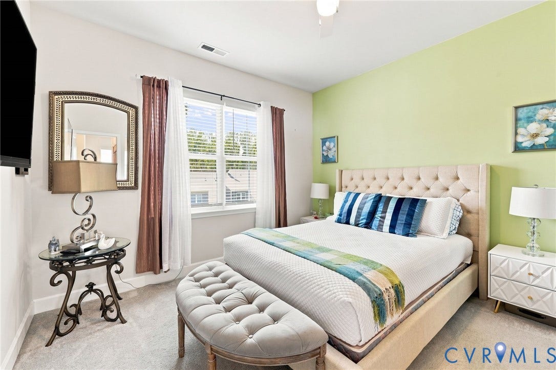 Bright bedroom featuring neutral carpet flooring and a light green accent wall