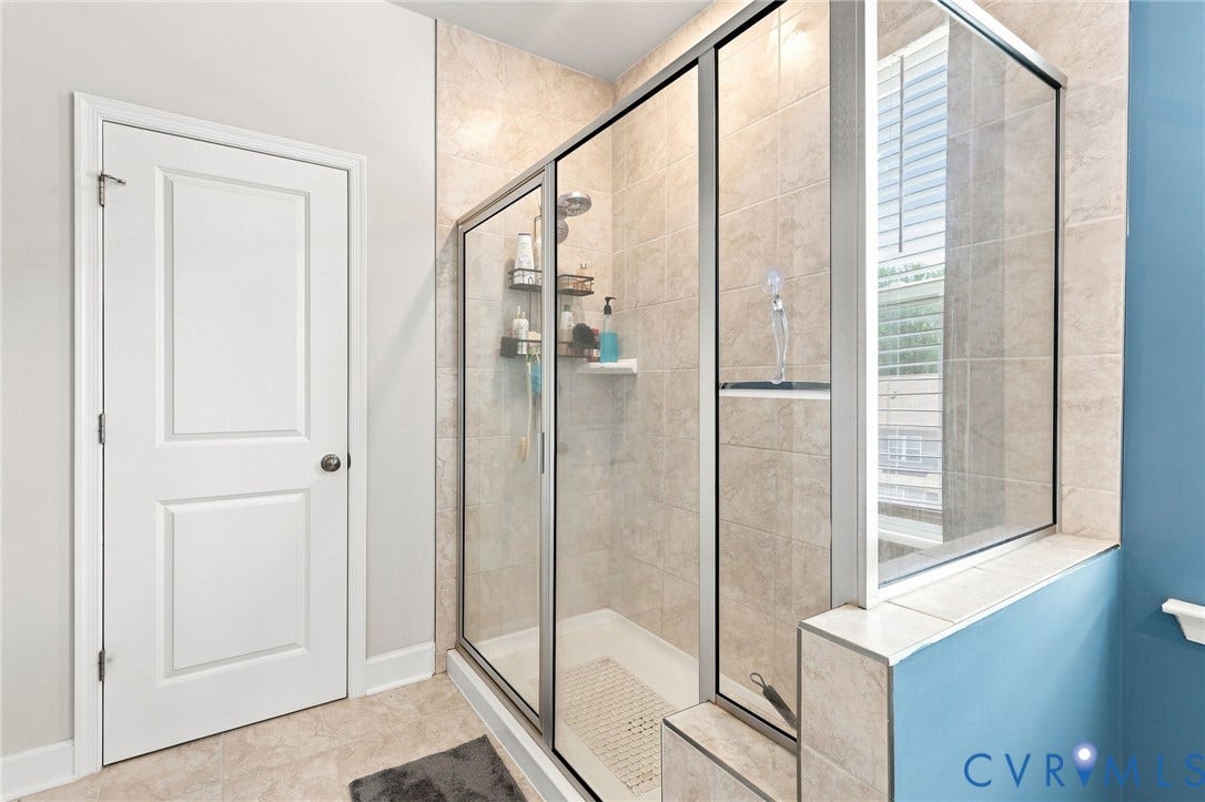 Walk-in shower with clear glass enclosure and light-toned tile surround