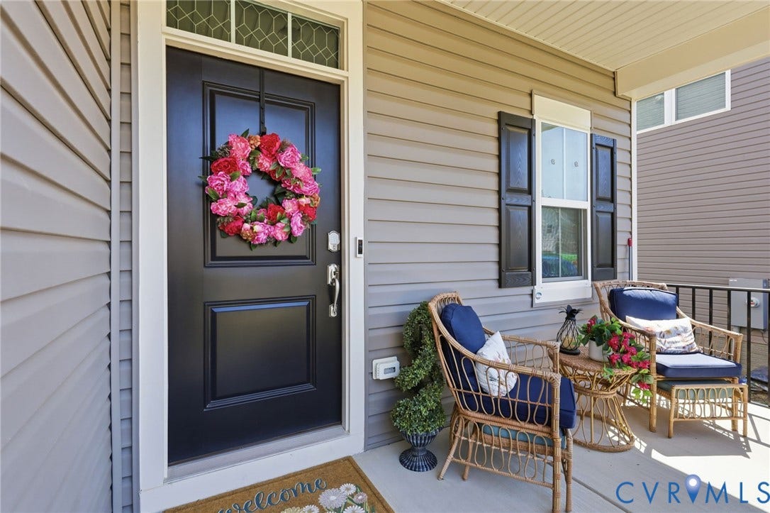 Welcoming front entry featuring a black paneled door with sidelight, topped with a vibrant seasonal wreath