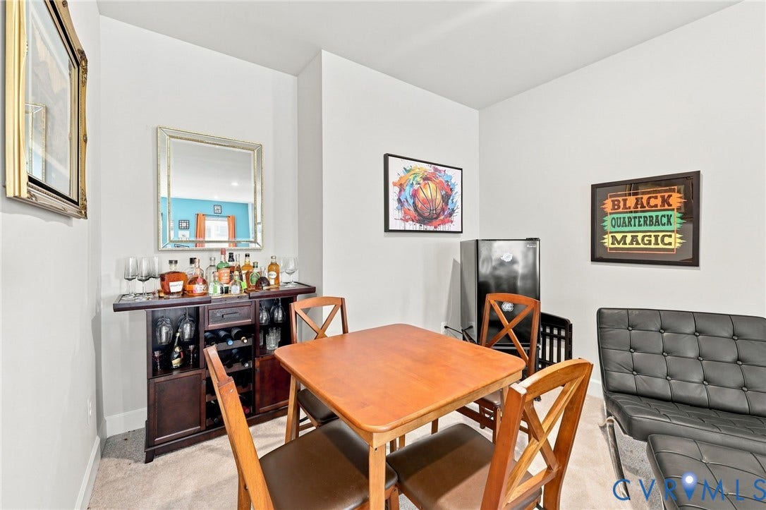 Dedicated entertainment area featuring a built-in dark wood beverage bar with cabinet storage, a mini-refrigerator, and neutral wall tones