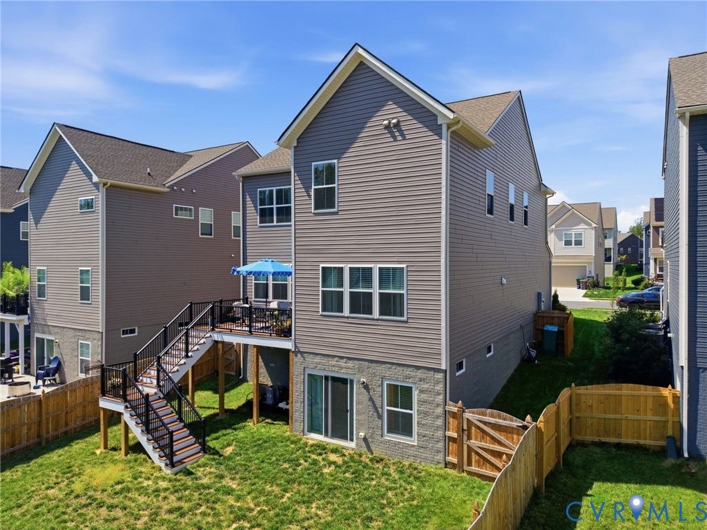 Two-story residence featuring a composite deck with integrated stair access, spacious rear yard with mature landscaping and wooden privacy fencing, and multi-pane windows throughout